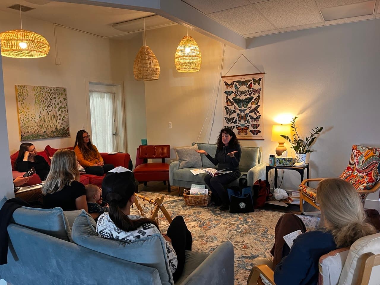 Tajali in conversation with a circle of parents in a cozy, lamplit room